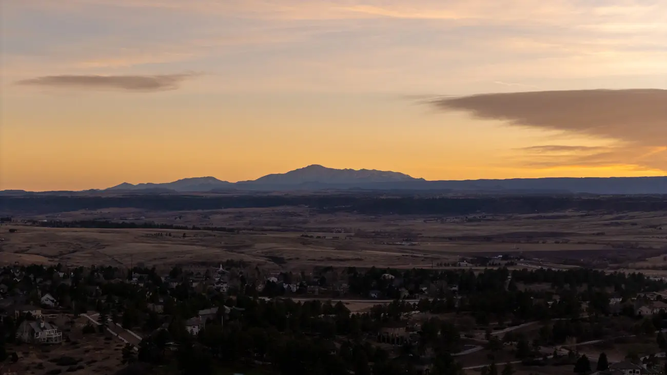 Homes and trees beneath a broad mountain horizon.